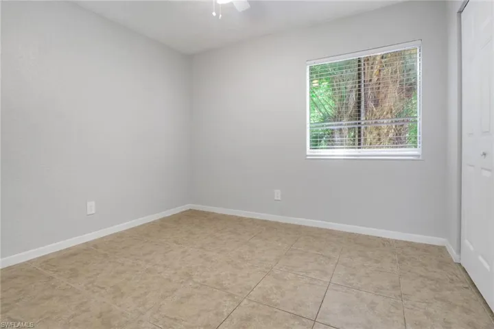 Spare room featuring baseboards, light tile patterned flooring, and a ceiling fan