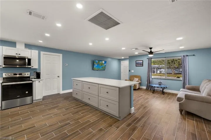 Kitchen with white cabinetry, ceiling fan, a kitchen island, and appliances with stainless steel finishes