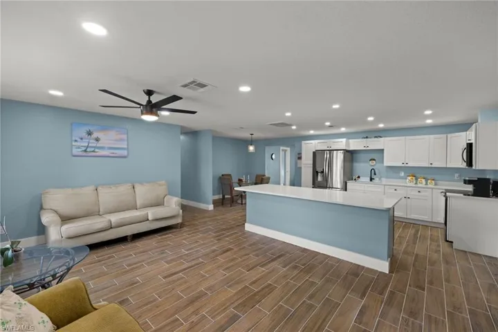 Kitchen featuring a center island, white cabinets, hanging light fixtures, ceiling fan, and appliances with stainless steel finishes