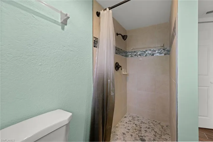 Bathroom featuring a shower with shower curtain and toilet