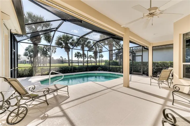 View of pool with screen enclosure, ceiling fan, and a patio