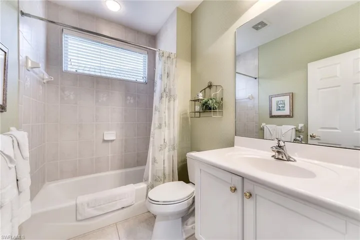 Full bathroom featuring tile patterned flooring, vanity, toilet, and shower / bath combo with shower curtain