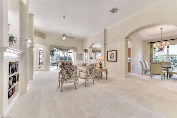 Living Room and Dining room with ceiling fan, light colored carpet, and ornamental molding