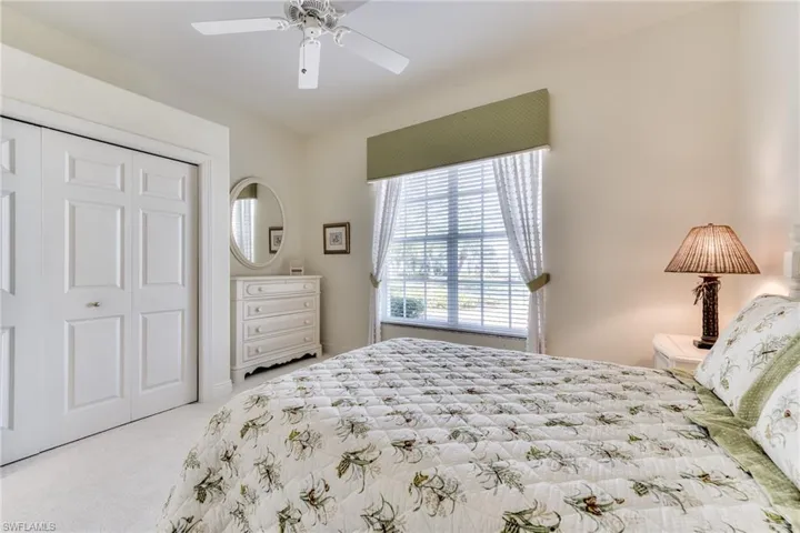 Bedroom with ceiling fan, light carpet, and a closet