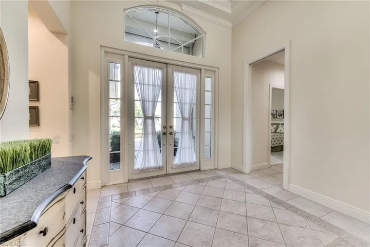 Foyer entrance with french doors, light tile patterned flooring, and ornamental molding