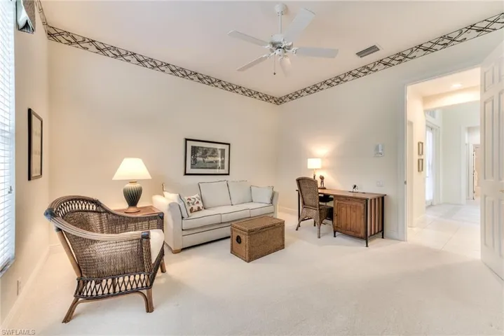 Carpeted den featuring ceiling fan