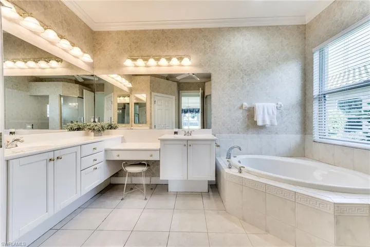 Primary bathroom featuring tile flooring, two sinks, a wealth of natural light