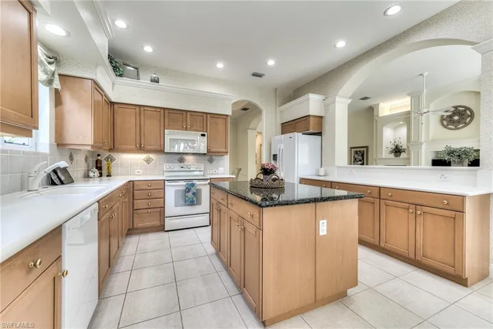 Kitchen featuring backsplash, white appliances, sink, and a center island