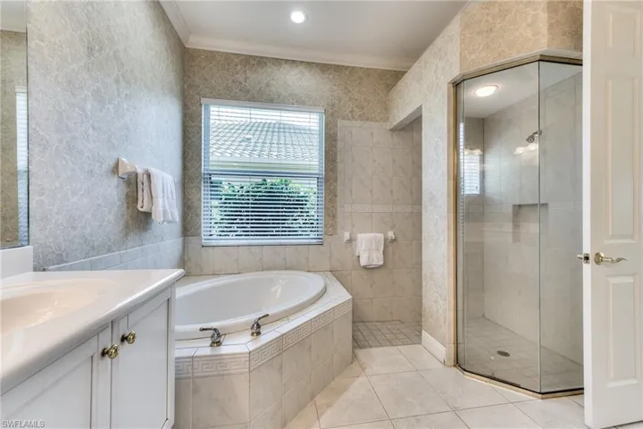 Bathroom featuring vanity, crown molding, tile flooring, and tub and walk in shower