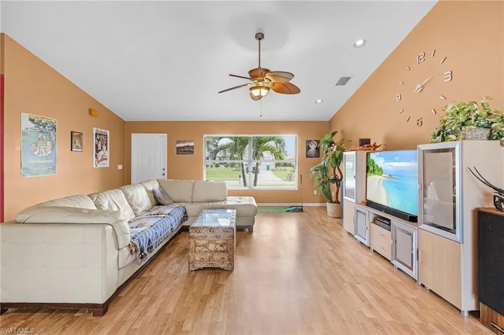 Living room featuring vaulted ceiling, light hardwood / wood-style flooring, and ceiling fan