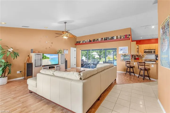 Living room featuring light hardwood / wood-style flooring, ceiling fan, vaulted ceiling, and track lighting