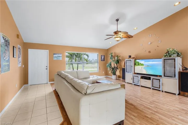 Living room featuring vaulted ceiling, ceiling fan, and light hardwood / wood-style floors