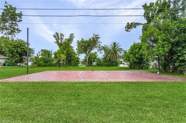 View of community featuring basketball court and a lawn