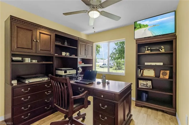Home office with light hardwood / wood-style floors and ceiling fan