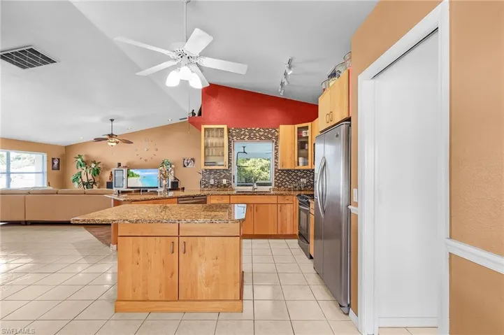 Kitchen featuring rail lighting, light tile patterned floors, a center island, ceiling fan, and appliances with stainless steel finishes