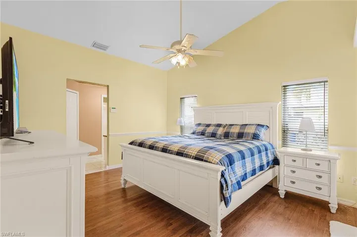 Bedroom featuring wood-type flooring, ceiling fan, and high vaulted ceiling
