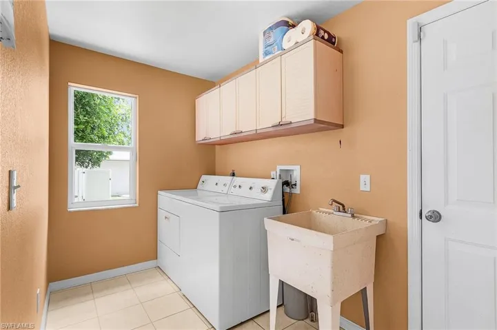 Laundry room featuring sink, cabinets, washer and dryer, and light tile patterned flooring