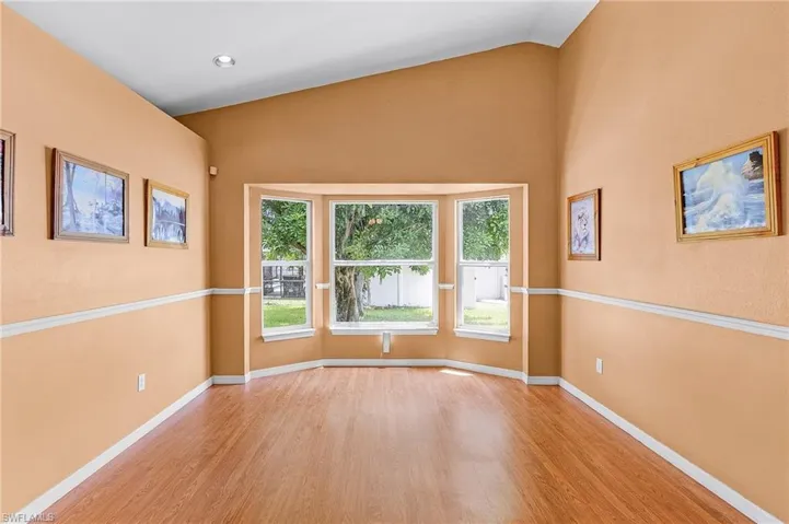 Empty room featuring vaulted ceiling and light wood-type flooring