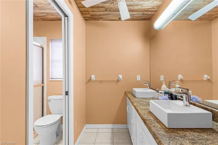 Bathroom with wooden ceiling, toilet, vanity, and ceiling fan