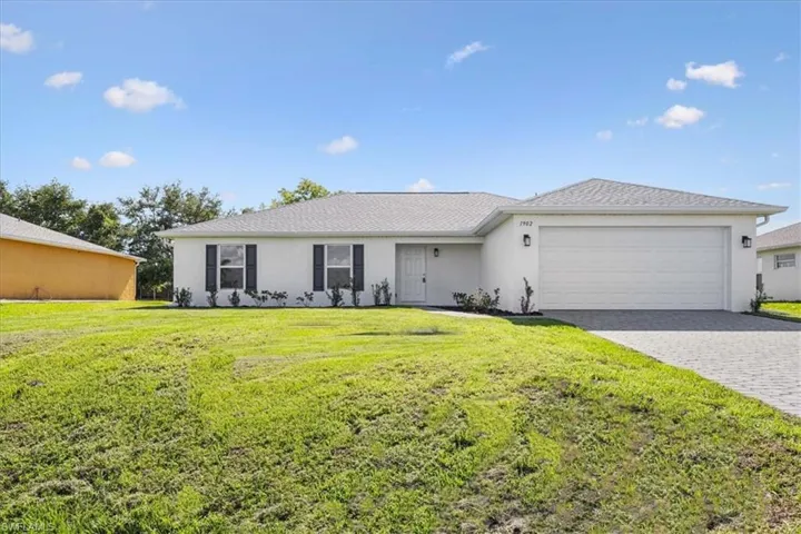 Ranch-style home featuring a garage and a front lawn