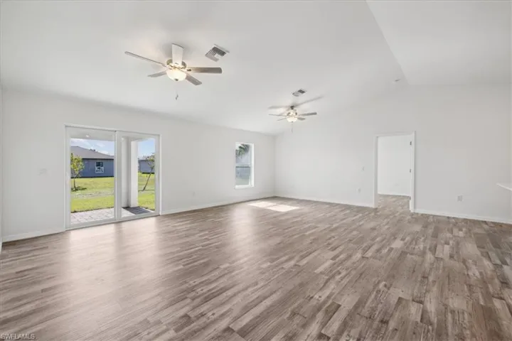 Unfurnished living room featuring ceiling fan, hardwood / wood-style flooring, and vaulted ceiling