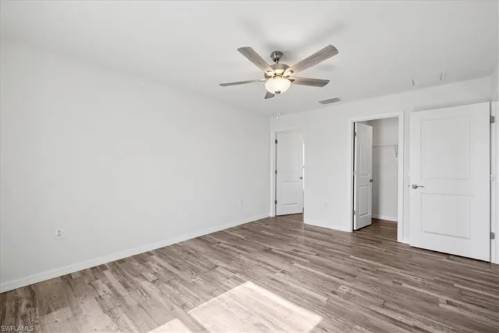 Unfurnished bedroom featuring a closet, ceiling fan, hardwood / wood-style floors, and a spacious closet