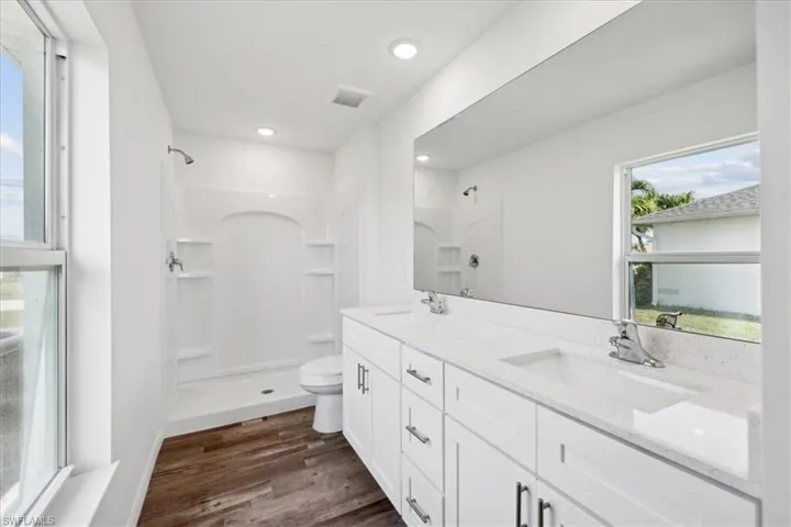 Bathroom featuring vanity, toilet, hardwood / wood-style flooring, and a shower