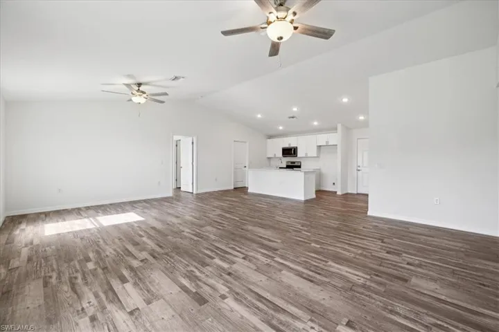 Unfurnished living room featuring ceiling fan, hardwood / wood-style flooring, and vaulted ceiling