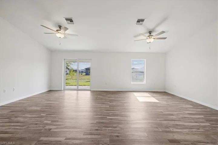 Empty room featuring ceiling fan and dark hardwood / wood-style floors