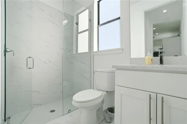 Bathroom featuring vanity, a marble finish shower, and recessed lighting