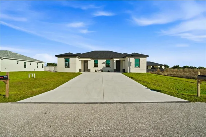 Prairie-style home featuring a front lawn, driveway, and stucco siding