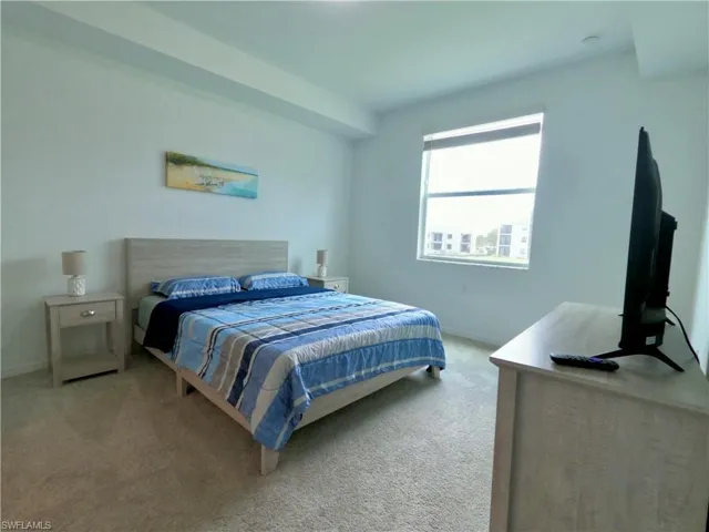 Bedroom featuring light carpet and baseboards