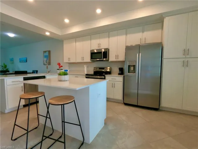Kitchen with white cabinets, appliances with stainless steel finishes, a breakfast bar, a center island, and recessed lighting