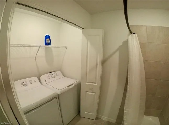 Laundry area with separate washer and dryer and tile patterned floors
