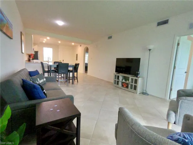 Living room featuring arched walkways, recessed lighting, and light tile patterned floors