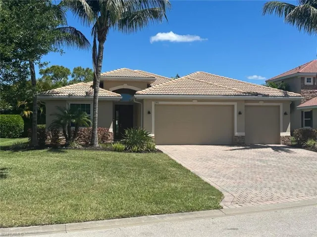 Single-story residence featuring a tile roof, a paver driveway, and a two-car garage