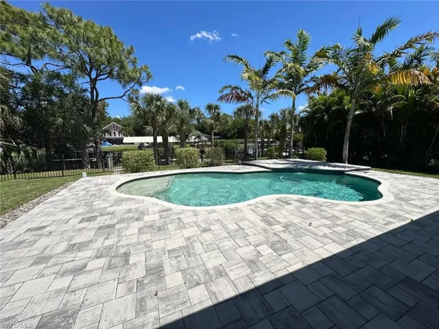 Freeform swimming pool surrounded by extensive paver decking