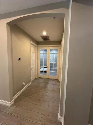 Hallway with wood-finish tile flooring, arched entryway, recessed lighting, and white baseboards