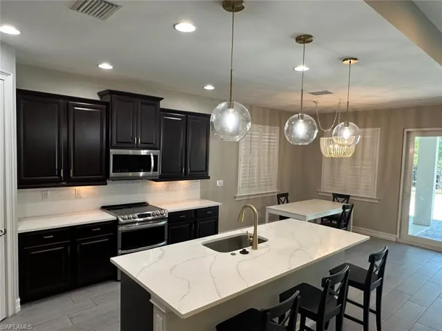 Contemporary kitchen featuring a large central island with seating, a gold-finish faucet, and a stainless steel undermount sink