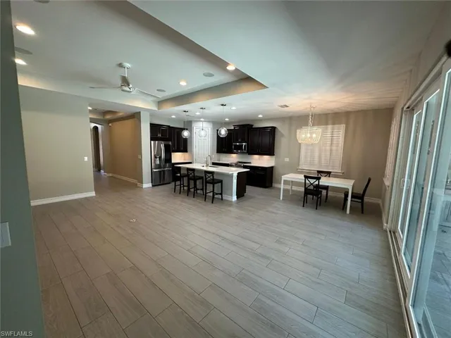 Open-concept living space featuring wood-finish tile flooring, recessed lighting, and a ceiling fan