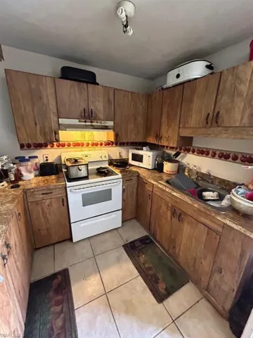 Kitchen featuring sink, extractor fan, white appliances, and light tile flooring