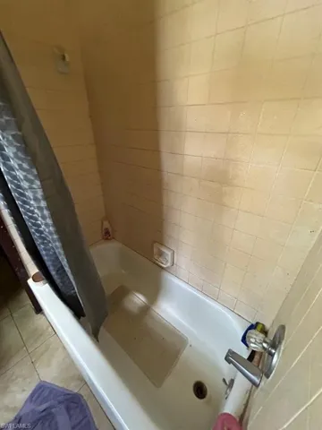 Bathroom with tile floors and shower / bath combination with curtain