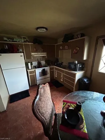 Kitchen with electric range, tile flooring, and white refrigerator