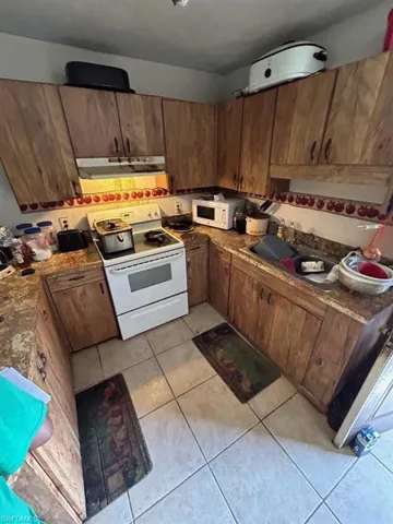 Kitchen with extractor fan, light tile flooring, and white appliances