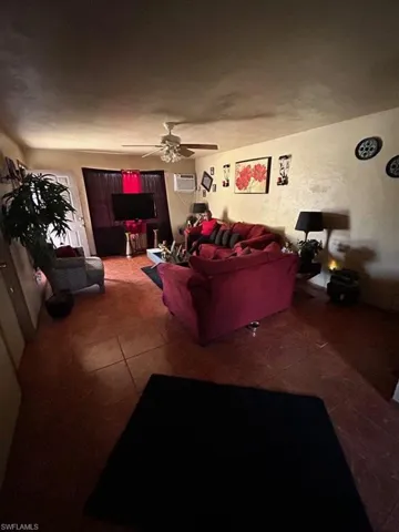 Tiled living room featuring a wall mounted AC and ceiling fan