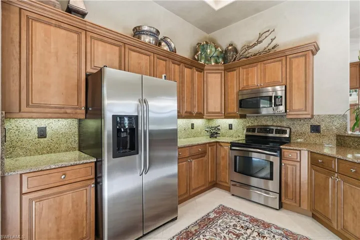 Warm wood cabinetry complements the kitchen, with a spacious walk-in pantry just beyond.
