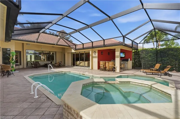 View of pool and entertainment area with bar, television and grill.