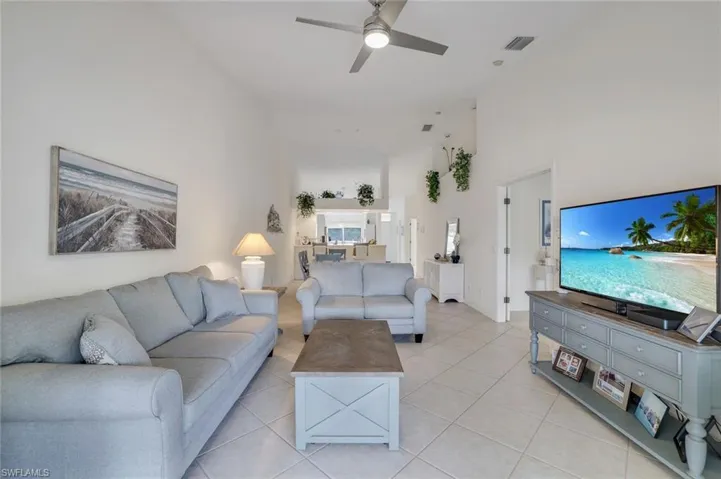 Tiled living room featuring new ceiling fan and high vaulted ceiling