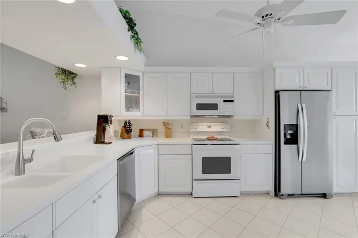 Large, Bright Kitchen featuring appliances with stainless steel finishes, vaulted ceiling, white cabinets
