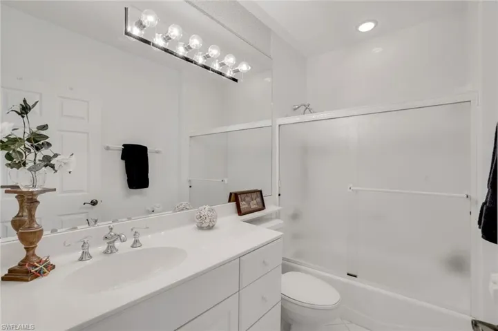 Full bathroom with tile patterned floors, shower / bath combination with glass door, vanity, and toilet